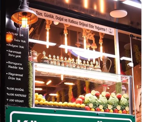 Dükkân vitrinindeki pano: Ketçap yok, Çin tuzu yok, Bulyon yok, Sarımsak tozu yok, Koruyucu madde yok, Hayvansal ürün yok.